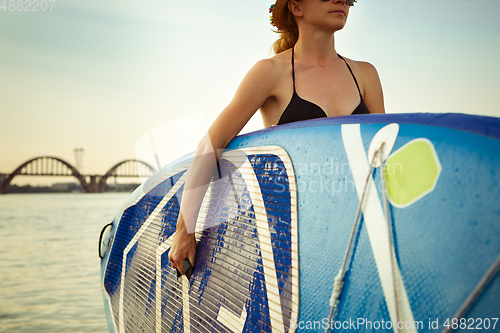 Image of Young attractive woman carries paddle board, SUP. Active life, sport, leisure activity concept