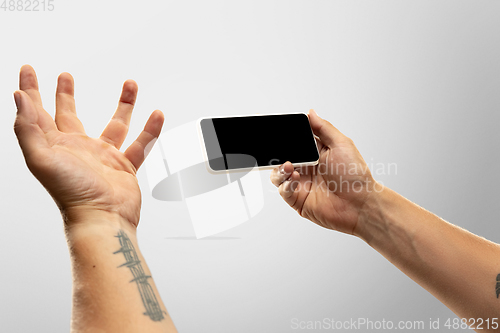 Image of Close up male hands holding phone with blank screen during online watching of popular sport matches and championships all around the world. Copyspace for ad