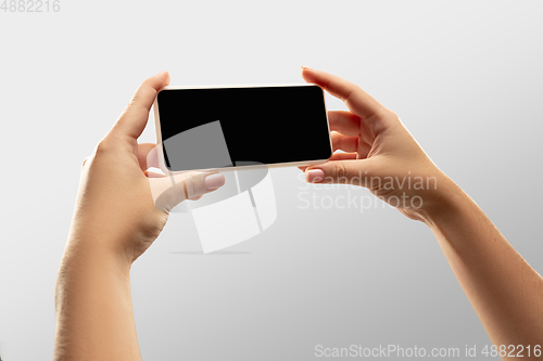 Image of Close up female hands holding smartphone with blank screen during online watching of popular sport matches and championships all around the world. Copyspace for ad