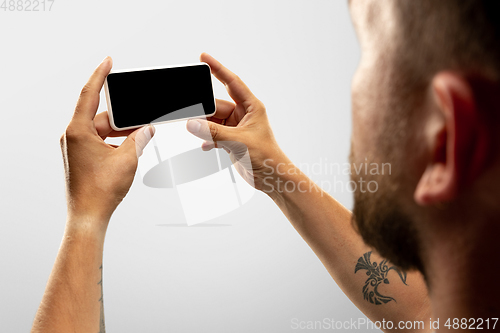 Image of Close up male hands holding phone with blank screen during online watching of popular sport matches and championships all around the world. Copyspace for ad