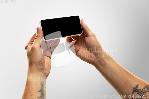 Image of Close up male hands holding phone with blank screen during online watching of popular sport matches and championships all around the world. Copyspace for ad