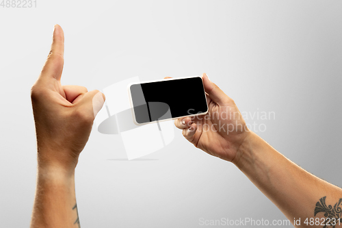 Image of Close up male hands holding phone with blank screen during online watching of popular sport matches and championships all around the world. Copyspace for ad