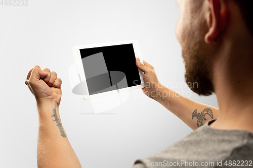 Image of Close up male hands holding tablet with blank screen during online watching of popular sport matches and championships all around the world. Copyspace for ad