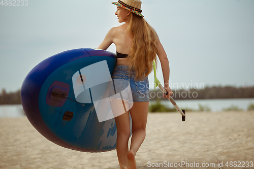 Image of Young attractive woman carries paddle board, SUP. Active life, sport, leisure activity concept