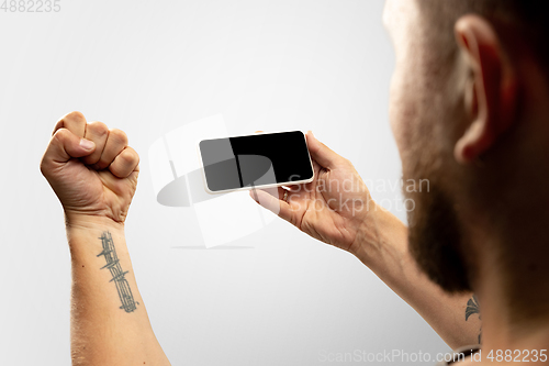 Image of Close up male hands holding phone with blank screen during online watching of popular sport matches and championships all around the world. Copyspace for ad