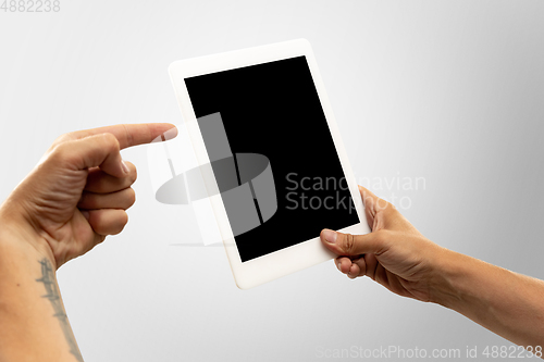 Image of Close up male hands holding tablet with blank screen during online watching of popular sport matches and championships all around the world. Copyspace for ad