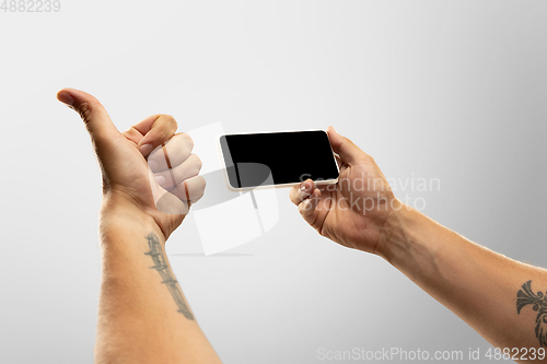 Image of Close up male hands holding phone with blank screen during online watching of popular sport matches and championships all around the world. Copyspace for ad