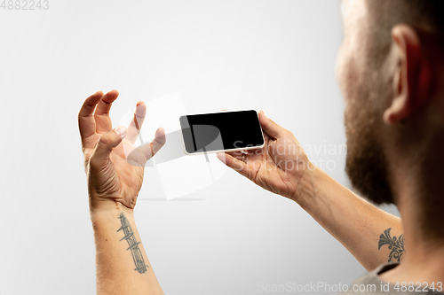 Image of Close up male hands holding phone with blank screen during online watching of popular sport matches and championships all around the world. Copyspace for ad