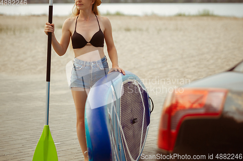 Image of Young attractive woman carries paddle board, SUP. Active life, sport, leisure activity concept