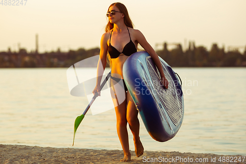 Image of Young attractive woman carries paddle board, SUP. Active life, sport, leisure activity concept