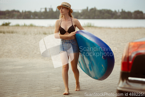 Image of Young attractive woman carries paddle board, SUP. Active life, sport, leisure activity concept