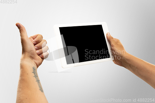 Image of Close up male hands holding tablet with blank screen during online watching of popular sport matches and championships all around the world. Copyspace for ad