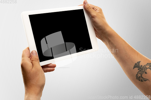 Image of Close up male hands holding tablet with blank screen during online watching of popular sport matches and championships all around the world. Copyspace for ad