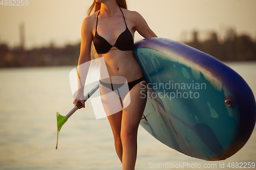 Image of Young attractive woman carries paddle board, SUP. Active life, sport, leisure activity concept