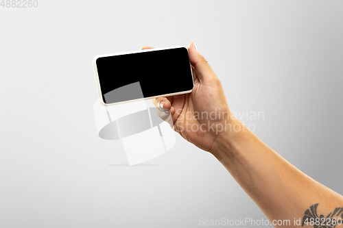 Image of Close up male hands holding phone with blank screen during online watching of popular sport matches and championships all around the world. Copyspace for ad