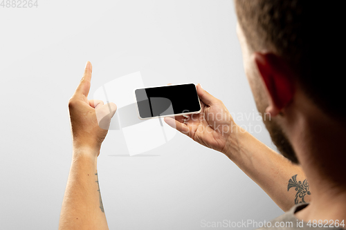 Image of Close up male hands holding phone with blank screen during online watching of popular sport matches and championships all around the world. Copyspace for ad