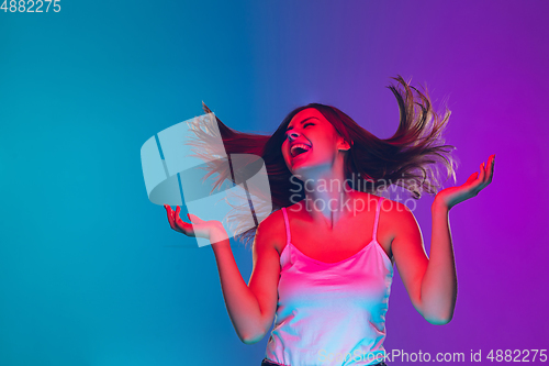 Image of Caucasian young woman\'s portrait isolated on gradient purple-blue background in neon light, cinema, movie watching