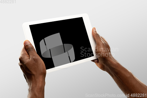 Image of Close up male hands holding tablet with blank screen during online watching of popular sport matches and championships all around the world. Copyspace for ad