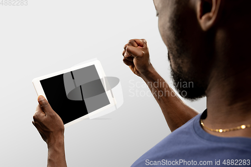 Image of Close up male hands holding tablet with blank screen during online watching of popular sport matches and championships all around the world. Copyspace for ad