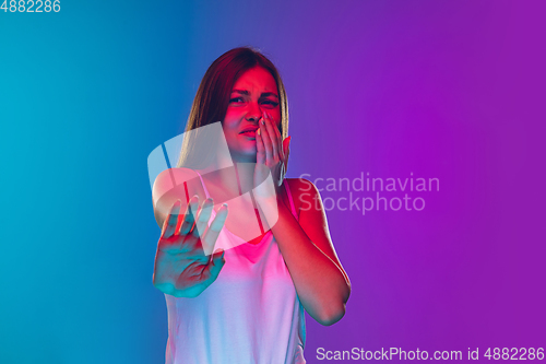 Image of Caucasian young woman\'s portrait isolated on gradient purple-blue background in neon light, cinema, movie watching