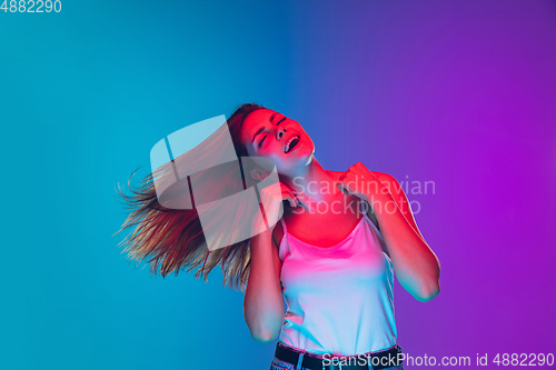 Image of Caucasian young woman\'s portrait isolated on gradient purple-blue background in neon light, cinema, movie watching