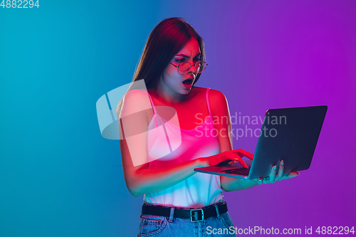 Image of Caucasian young woman\'s portrait isolated on gradient purple-blue background in neon light, cinema, movie watching