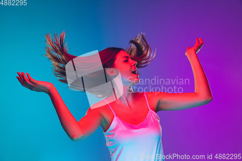 Image of Caucasian young woman\'s portrait isolated on gradient purple-blue background in neon light, cinema, movie watching