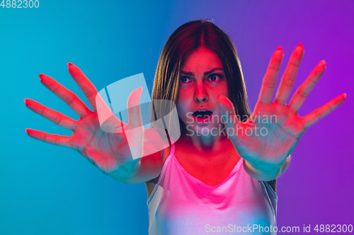 Image of Caucasian young woman\'s portrait isolated on gradient purple-blue background in neon light, cinema, movie watching