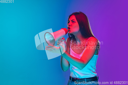 Image of Caucasian young woman\'s portrait isolated on gradient purple-blue background in neon light, cinema, movie watching