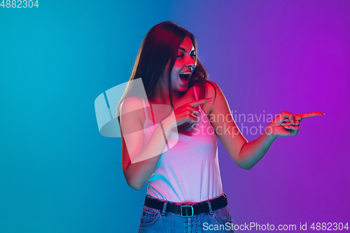 Image of Caucasian young woman\'s portrait isolated on gradient purple-blue background in neon light, cinema, movie watching