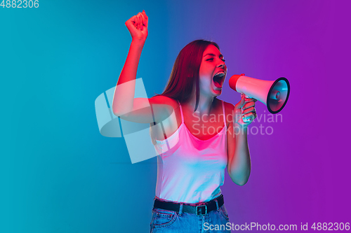Image of Caucasian young woman\'s portrait isolated on gradient purple-blue background in neon light, cinema, movie watching