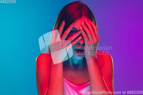 Image of Caucasian young woman\'s portrait isolated on gradient purple-blue background in neon light, cinema, movie watching