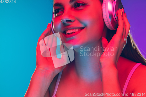 Image of Caucasian young woman\'s portrait isolated on gradient purple-blue background in neon light