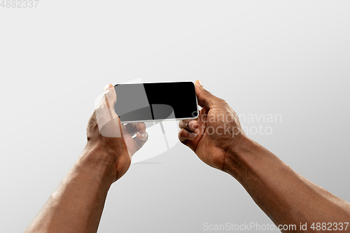 Image of Close up male hands holding smartphone with blank screen during online watching of popular sport matches and championships all around the world. Copyspace for ad