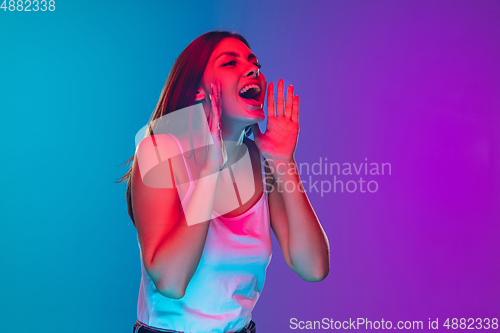 Image of Caucasian young woman\'s portrait isolated on gradient purple-blue background in neon light, cinema, movie watching