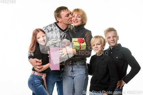 Image of Children and dad congratulated mom on her birthday by giving her gifts, dad kisses mom