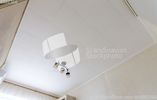 Image of Modest ceiling with glued ceiling tiles and a small chandelier