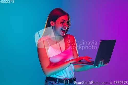 Image of Caucasian young woman\'s portrait isolated on gradient purple-blue background in neon light, cinema, movie watching