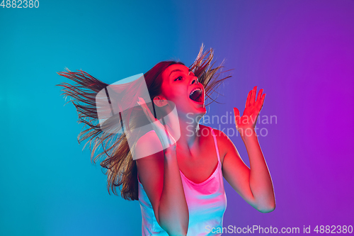 Image of Caucasian young woman\'s portrait isolated on gradient purple-blue background in neon light, cinema, movie watching