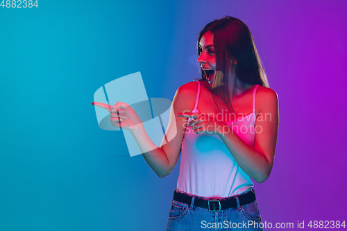 Image of Caucasian young woman\'s portrait isolated on gradient purple-blue background in neon light, cinema, movie watching