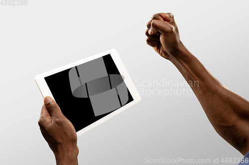 Image of Close up male hands holding tablet with blank screen during online watching of popular sport matches and championships all around the world. Copyspace for ad