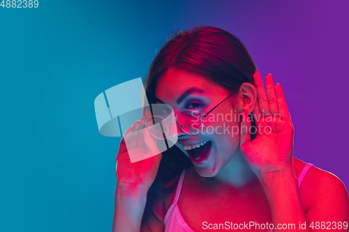 Image of Caucasian young woman\'s portrait isolated on gradient purple-blue background in neon light, cinema, movie watching