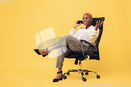 Image of Young african-american woman in casual wear on yellow background. Bodypositive female character, plus size businesswoman