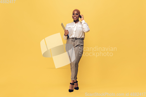 Image of Young african-american woman in casual wear on yellow background. Bodypositive female character, plus size businesswoman
