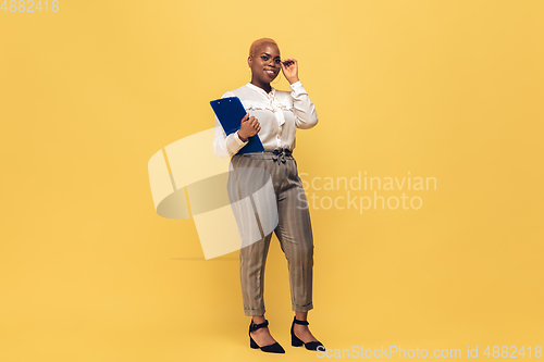 Image of Young african-american woman in casual wear on yellow background. Bodypositive female character, plus size businesswoman