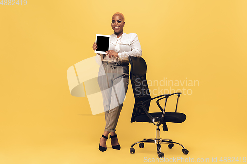 Image of Young african-american woman in casual wear on yellow background. Bodypositive female character, plus size businesswoman