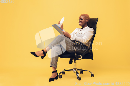 Image of Young african-american woman in casual wear on yellow background. Bodypositive female character, plus size businesswoman