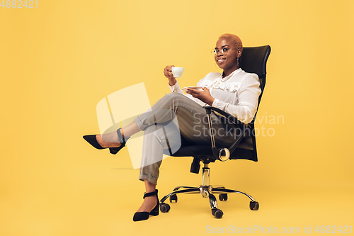 Image of Young african-american woman in casual wear on yellow background. Bodypositive female character, plus size businesswoman