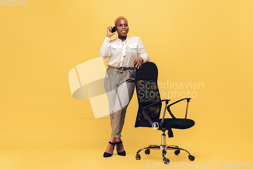 Image of Young african-american woman in casual wear on yellow background. Bodypositive female character, plus size businesswoman