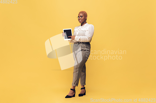 Image of Young african-american woman in casual wear on yellow background. Bodypositive female character, plus size businesswoman